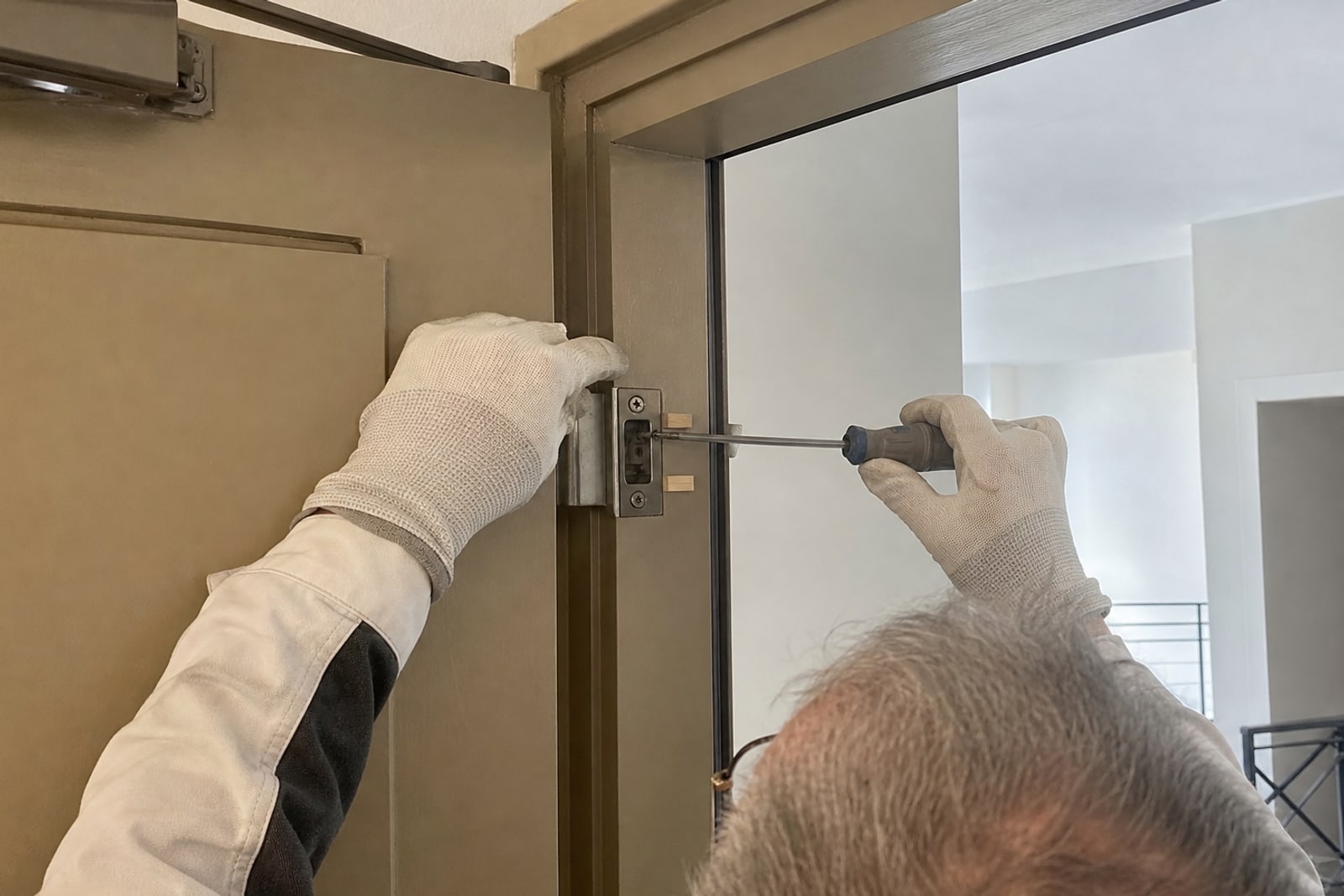mains réglant la gâche d'une porte